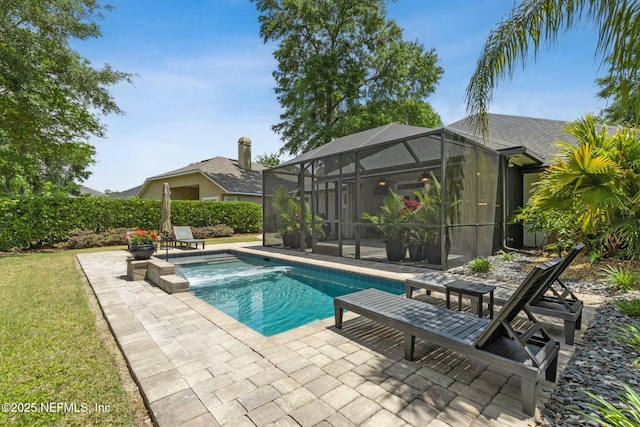 pool featuring a lawn, glass enclosure, and a patio area