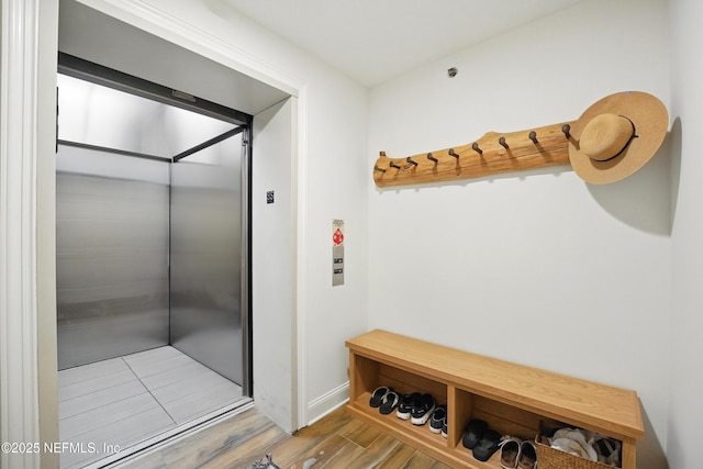 mudroom featuring elevator, wood finished floors, and baseboards