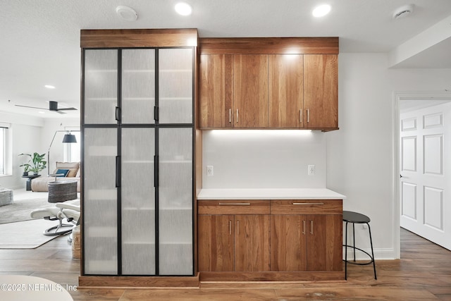 kitchen with brown cabinets, light countertops, wood finished floors, and recessed lighting