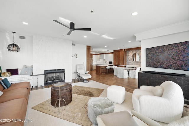 living area featuring recessed lighting, wood finished floors, a ceiling fan, and a fireplace
