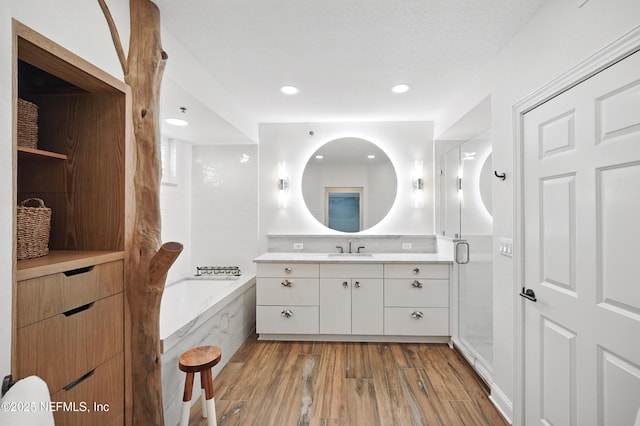full bathroom featuring vanity, a bathtub, wood finished floors, a stall shower, and recessed lighting