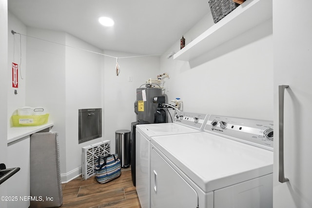 washroom with washing machine and clothes dryer, electric water heater, dark wood finished floors, and baseboards