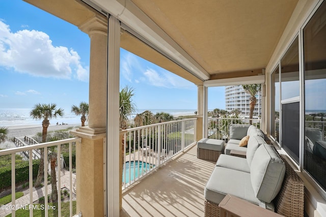 balcony featuring view of water and beach and view of pool area