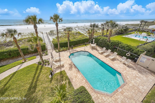 community pool with view of water and beach and a patio area