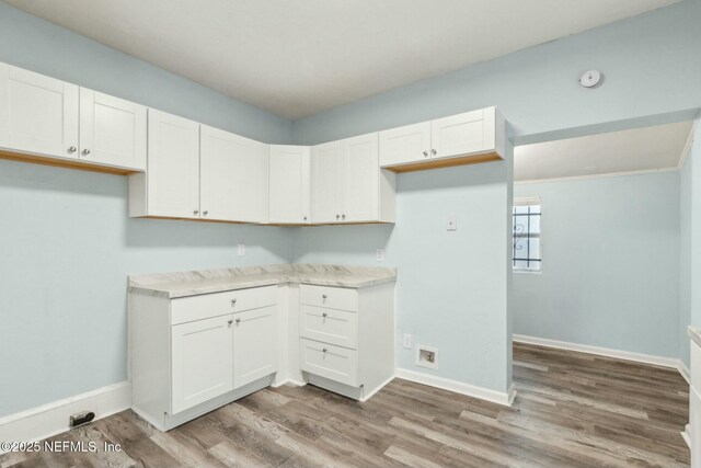 kitchen featuring light countertops, baseboards, light wood-style floors, and white cabinetry