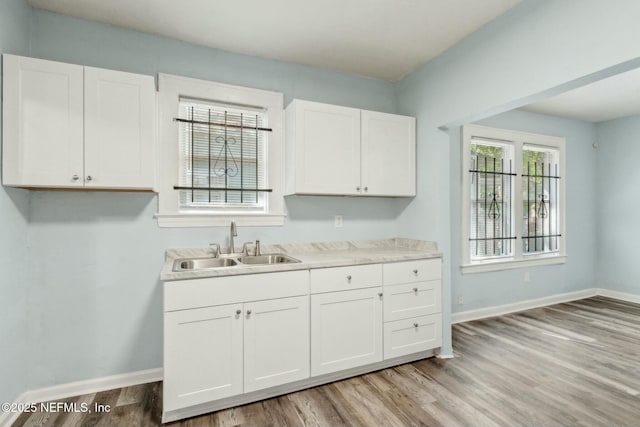 kitchen featuring light countertops, light wood finished floors, white cabinetry, and a sink