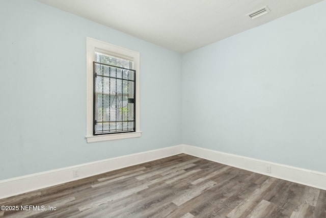 unfurnished room with wood finished floors, visible vents, and baseboards