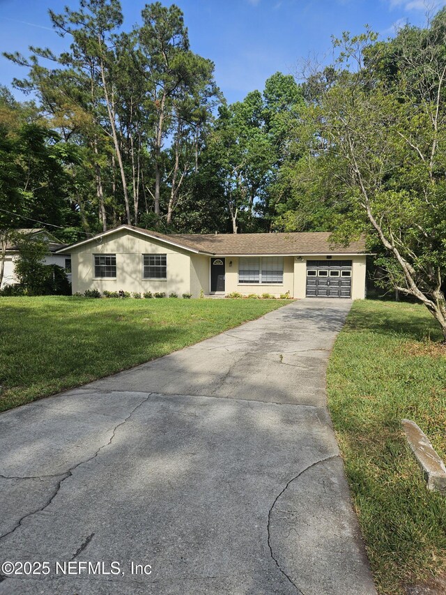single story home featuring a front lawn, driveway, an attached garage, and stucco siding