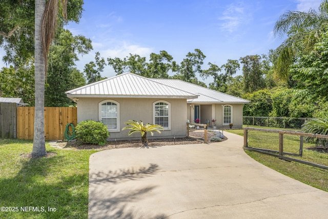 view of front facade featuring metal roof, a front lawn, and stucco siding