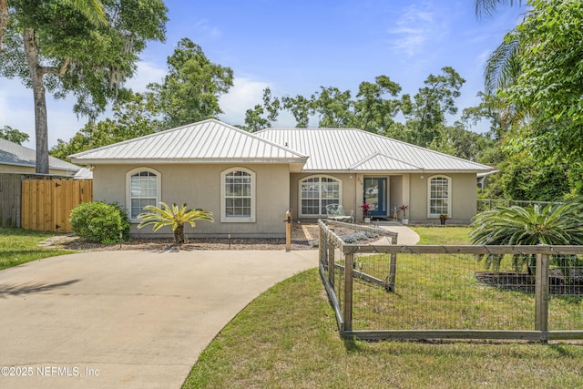 single story home with a front lawn, stucco siding, fence, and metal roof