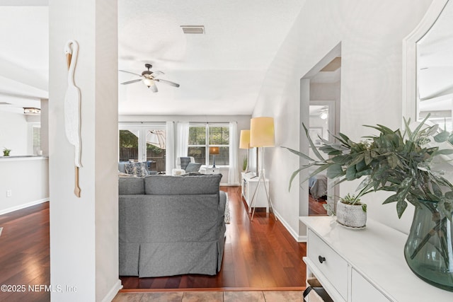 living area with ceiling fan, visible vents, baseboards, and dark wood-type flooring