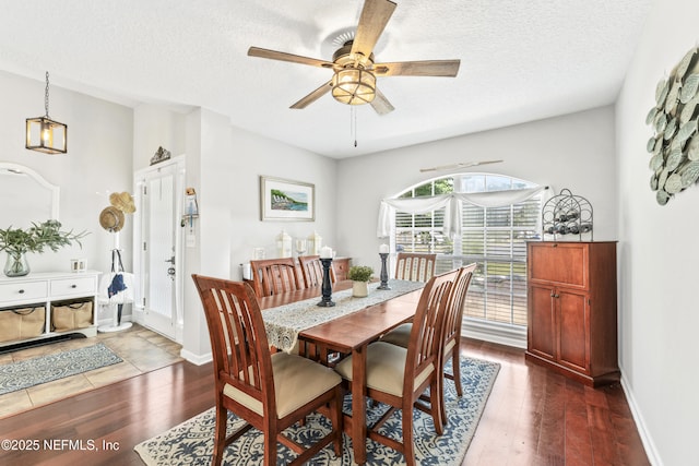 dining space featuring baseboards, a textured ceiling, ceiling fan, and dark wood-style floors