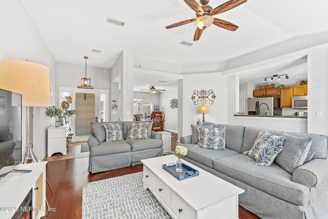 living room featuring baseboards, ceiling fan, visible vents, and wood finished floors