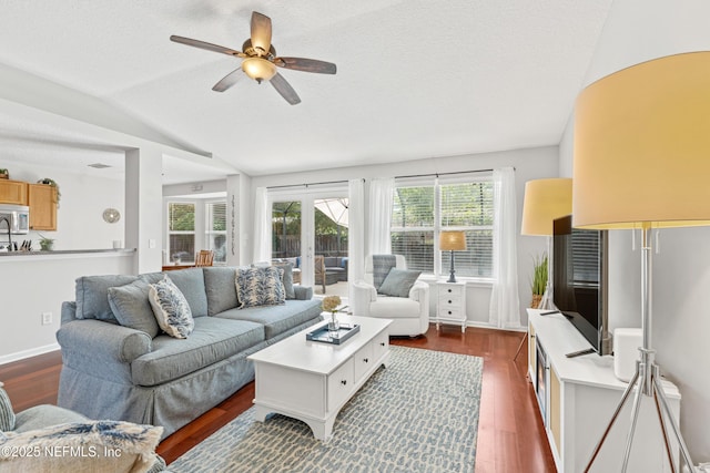 living room with a ceiling fan, a textured ceiling, dark wood finished floors, and vaulted ceiling