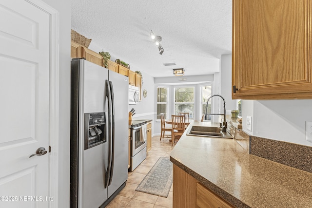 kitchen featuring a sink, a textured ceiling, stainless steel appliances, light tile patterned floors, and visible vents