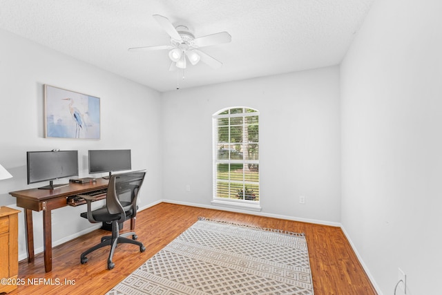 home office featuring a textured ceiling, baseboards, a ceiling fan, and wood finished floors