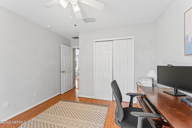 home office featuring a ceiling fan, light wood-type flooring, and visible vents