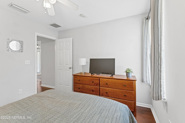 bedroom with baseboards, a ceiling fan, dark wood finished floors, and visible vents