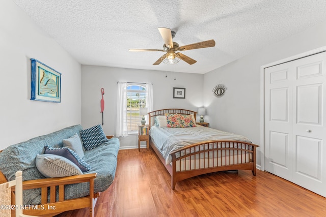 bedroom featuring baseboards, a textured ceiling, ceiling fan, and light wood-style flooring