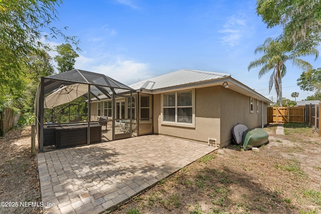 rear view of house featuring a patio, a fenced backyard, stucco siding, a jacuzzi, and a lanai