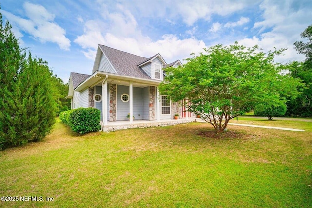 new england style home with a porch, a front lawn, and stone siding