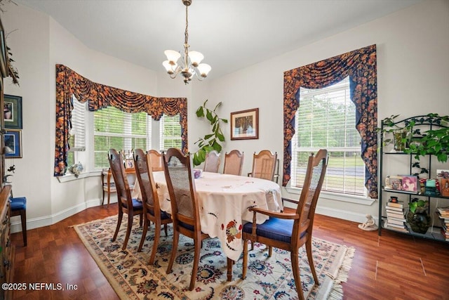 dining area with a wealth of natural light, wood finished floors, a notable chandelier, and baseboards