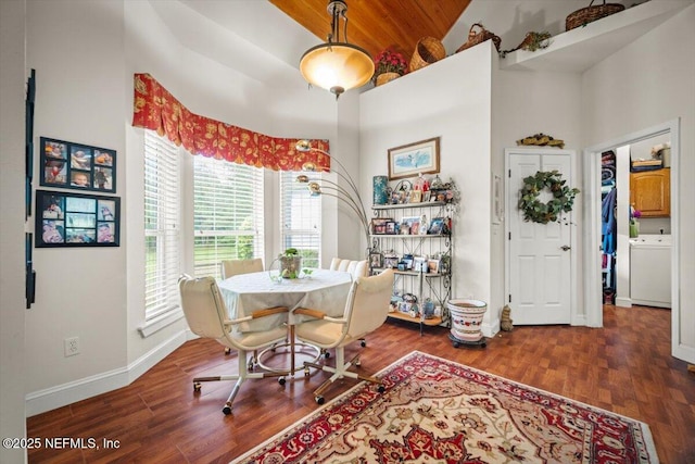 dining area with wooden ceiling, washer / clothes dryer, baseboards, a towering ceiling, and wood finished floors