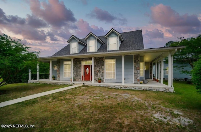 view of front of property featuring covered porch, a lawn, and stone siding