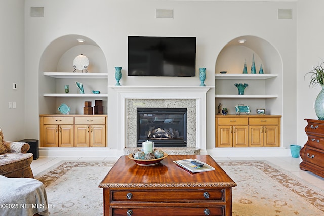 living room featuring visible vents, baseboards, built in features, and a fireplace