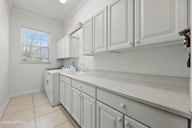 washroom with crown molding, a sink, baseboards, separate washer and dryer, and cabinet space