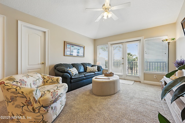 living area featuring baseboards, a ceiling fan, and carpet