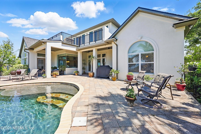 back of house featuring a patio area, a balcony, a ceiling fan, and stucco siding