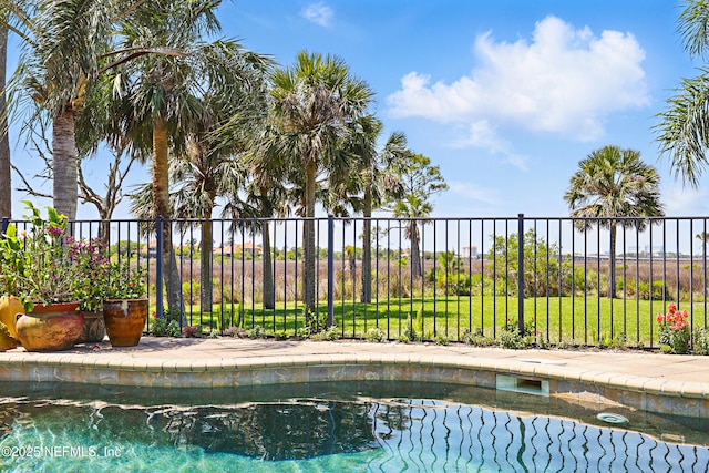 view of swimming pool featuring fence and a yard