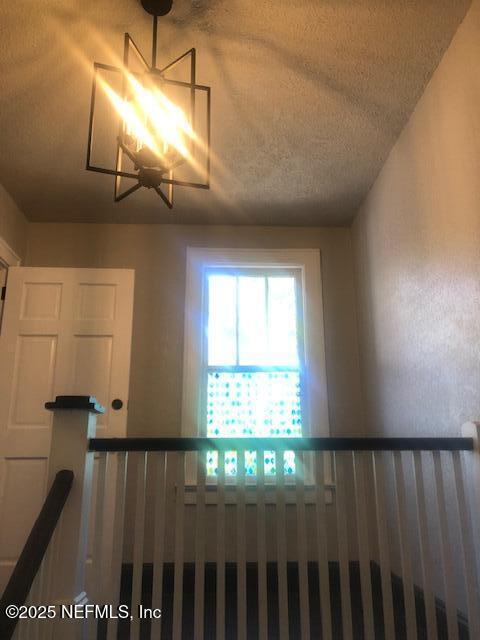 stairs with an inviting chandelier and a textured ceiling