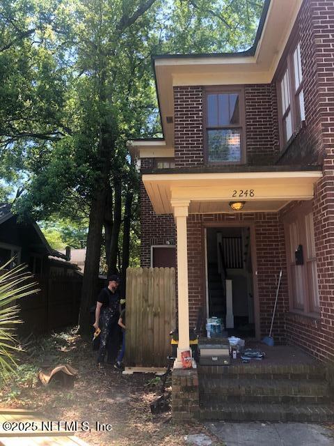 property entrance with covered porch and brick siding