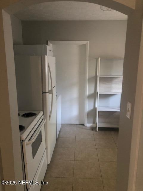 kitchen featuring tile patterned flooring, white cabinetry, and white appliances