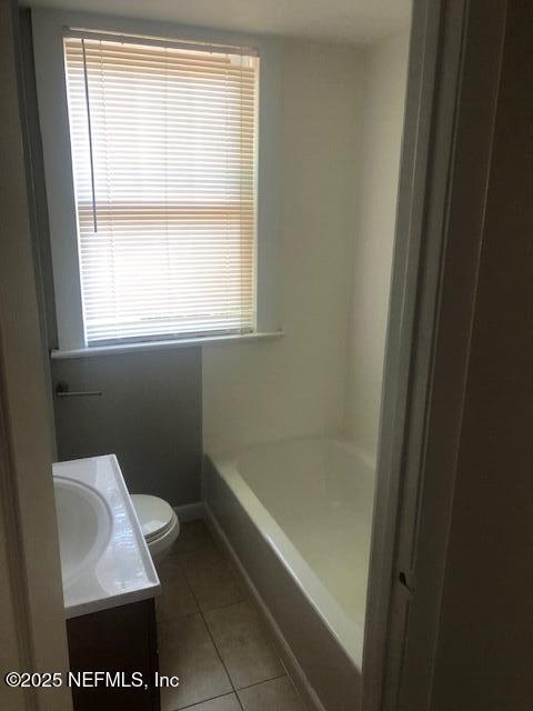 full bathroom featuring a bathtub, tile patterned flooring, vanity, and toilet