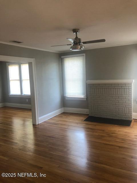 spare room with baseboards, a healthy amount of sunlight, wood finished floors, and visible vents