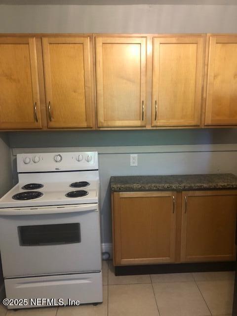 kitchen with white electric range oven and light tile patterned floors