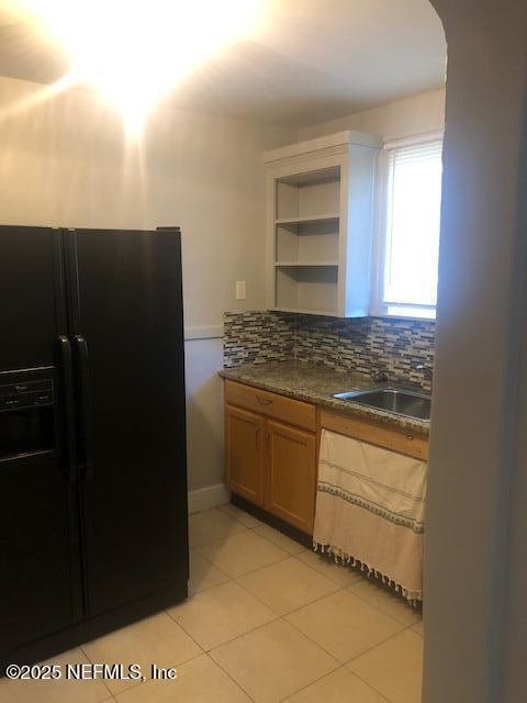 kitchen with open shelves, a sink, decorative backsplash, black fridge with ice dispenser, and light tile patterned floors