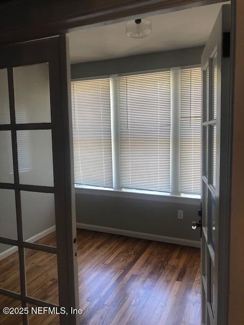 spare room with dark wood-type flooring and baseboards