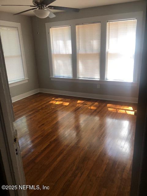 empty room featuring baseboards, a ceiling fan, and wood finished floors