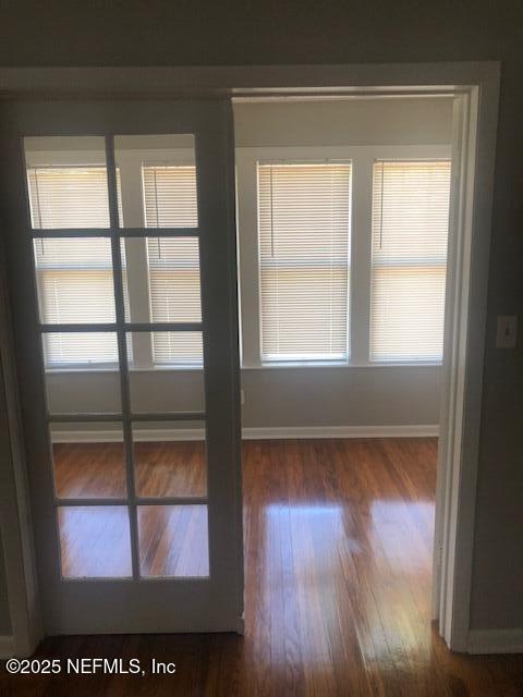 unfurnished room featuring wood finished floors, a wealth of natural light, and baseboards