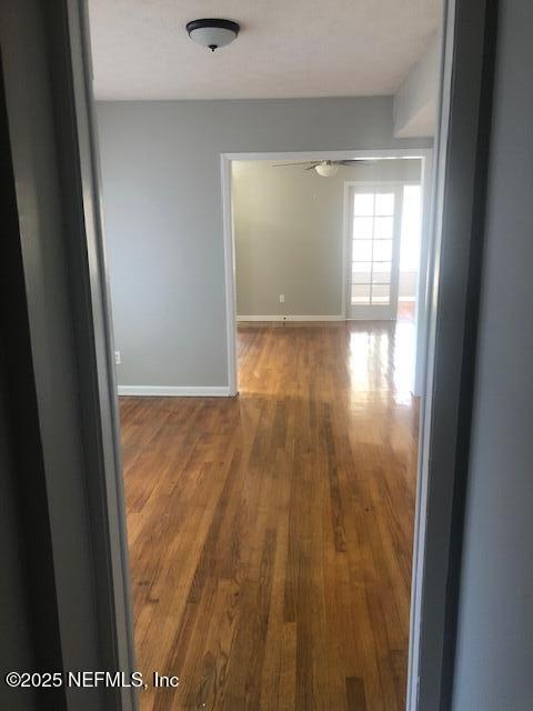 corridor with baseboards and wood finished floors