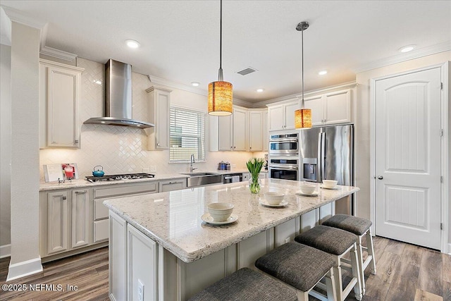 kitchen with a sink, decorative backsplash, wood finished floors, and wall chimney range hood