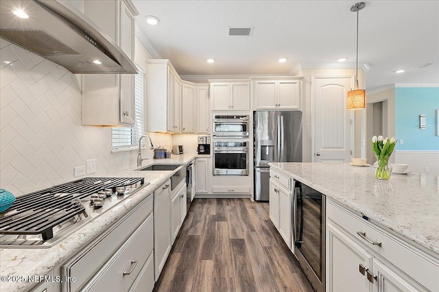 kitchen with appliances with stainless steel finishes, a sink, beverage cooler, wall chimney exhaust hood, and dark wood-type flooring