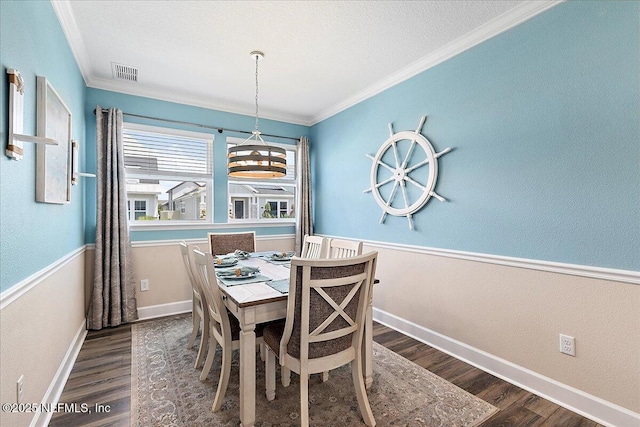 dining space with crown molding, a chandelier, visible vents, and wood finished floors
