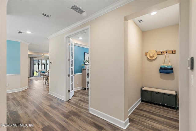 hall with visible vents, ornamental molding, and wood finished floors