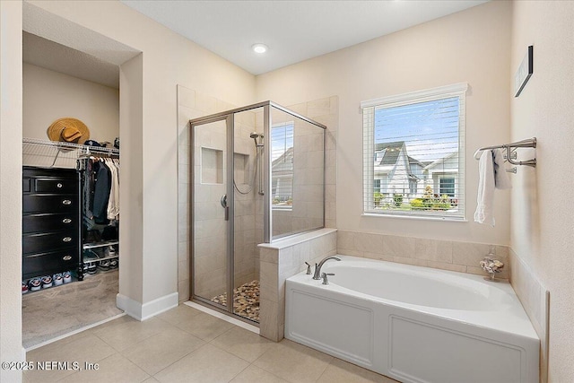 bathroom with a garden tub, tile patterned flooring, a walk in closet, and a stall shower