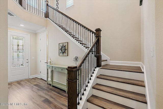 staircase with crown molding, baseboards, and wood finished floors
